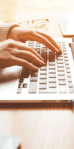 A close up of hands typing on the keyboard of a laptop
